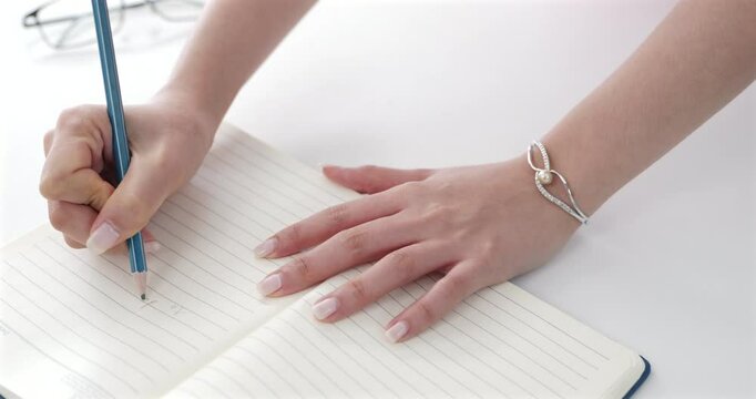 Close-up of a woman’s hand writing her daily to-do list in a book. Ideal for content on productivity, organization, lifestyle, and self-management, task prioritization and effective work habits