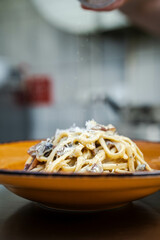 A creamy truffle pasta dish served on a vibrant yellow plate. It is ideal for promoting gourmet pasta offerings or fine dining experiences with a pop of color.
