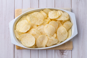 Potato chips in a plate over wooden table