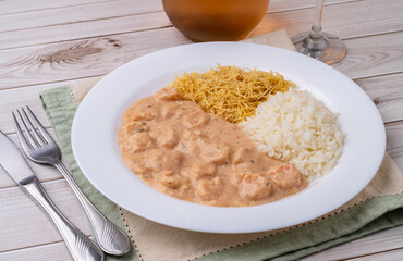 Shrimp strogonoff with rice and straw potato over wooden table
