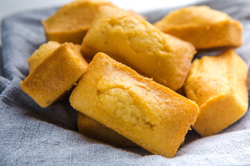 Close-up of corn muffins on plate with bowl of corn meal and additional muffins in the background.