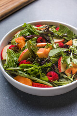 Fresh vegetable salad plate of  papaya, leaves raspberry and apple. Healthy food. Diet dinner or lunch menu. Salad plate on table. Flat lay.