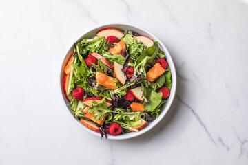 Tasty salad with apple, papaya, lettuce, top view.  Vegetable salad.