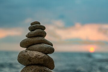 Rocks Stack Sunset Beach - A balanced stack of rocks stands against a beautiful sunset over a calm ocean.