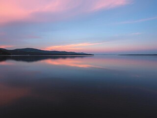 A serene sunset over a calm lake, with vibrant orange and pink hues reflecting in the water, sky, peaceful