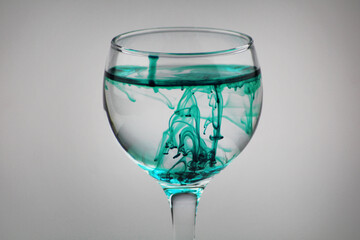 Green turquoise Ink in a wine glass with clean water