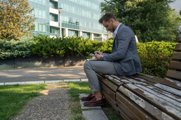 Businessman hand working with new modern computer and writing. accounting concept. Businessman working using calculator with money stack in park. Attractive smiling businessman working