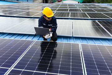 Engineer checking solar cell  or photovoltaic cell by computer laptop installed on the roof of the factory. Technician worker repair or inspect the system. Industrial renewable energy concept