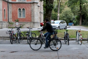 Salzburg, Austria - October 1 2024: Blurred Cyclist Riding Past Parked Bicycles on a Quiet Street in a European Neighborhood