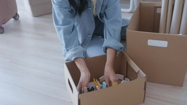 young woman is unpacking her belongings to move into her dorm in preparation for university
