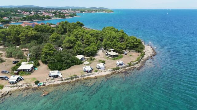 Small camp hidden among pine trees on cape on Ugljan island in Adriatic sea near Zadar in Croatia. Camping, summer vacation, tourism and travel concepts. 4K, 60FPS