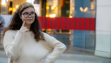 Young white girl with glasses, yellow headscarf and casual clothes thinks