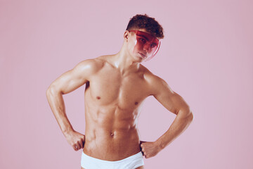 Fototapeta premium Confident young man posing with pink background, wearing only white briefs and stylish sunglasses. Fashion and summer vibes concept.