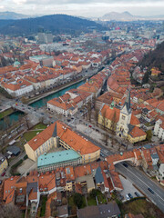 Obraz premium Ljubljana old town above Karlovška cesta road with Church of St. James. Aerial vertical view of the capital city of Slovenia in the winter. Roznik hill and Smarna Gora at distance.
