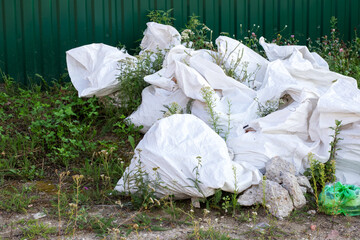 Fototapeta premium There is a large pile of white bags that are laying on the ground in the grass