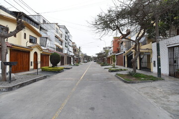 Obraz premium calle de zona residencial frente a via de doble sentido en lima peru con areas verdes, arboles y señalizacion para autos