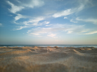 Close-up view of the sand on the beach with ocean and cirrus clouds in the background