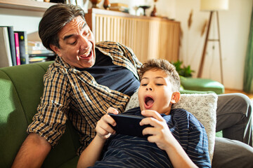 Father and son bonding while playing video games on phone at home