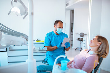 Fototapeta premium Young woman having dental work done on her teeth in a dentists office by her male dentist