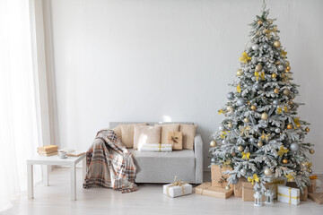 Snow-covered Christmas tree with gifts decorated with toys in the interior of a white room for the new year