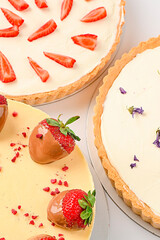 Three homemade pies, gluten free, with strawberries in chocolate, with cream on top, on a white background