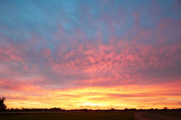 Pink blue color of the sunset sky with clouds above the dark horizon