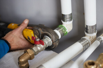 A worker connects pipes. Hand press for the water industry.