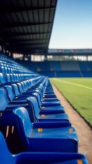 Fototapeta premium Empty blue stadium seats line the field under a clear sky during a sunny day