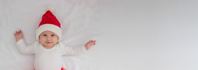 Baby girl in a Santa hat on a light background.holiday.