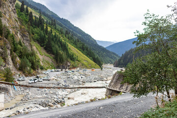 MESTIA GEORGIA - AUGUST 22, 2024: Chalaadi glacier bridge and parking for tourists car and buses.