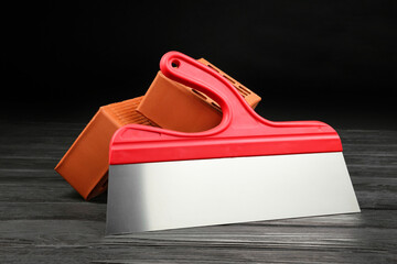 Red bricks and putty knife on wooden table. Building material