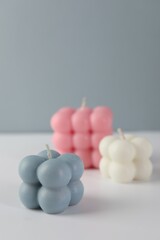 Beautiful bubble candles on white table against grey background