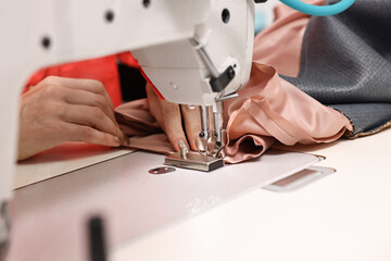 Woman working with sewing machine in professional workshop, closeup
