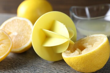 Plastic juicer and fresh lemons on grey wooden table, closeup