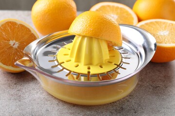 Juicer and oranges on grey table, closeup