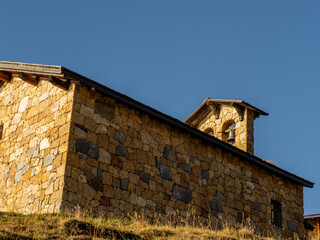 chapelle du lac de roselend au soleil couchant, avec son clocheton &agrave; deux cloches et ses pierres dor&eacute;es