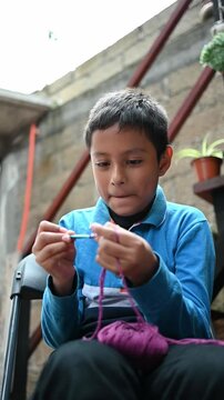 Mexican boy smiling as he learns to crochet