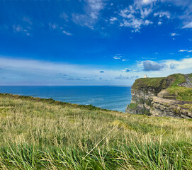 Ireland s rugged coastline, rocky shore meets expansive blue ocean under clear skies, breathtaking...