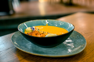 Pumpkin puree soup with shrimp in a plate. Concept of autumn cuisine. Pumpkin dish