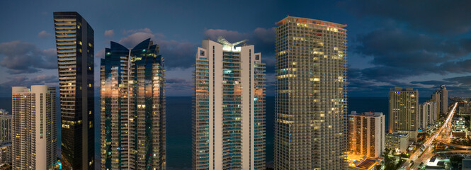 Night urban landscape of downtown district in Sunny Isles Beach city in Florida, USA. Skyline with brightly illuminated high skyscraper buildings in modern american megapolis