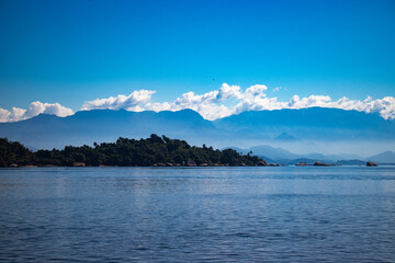 Blue sky with clouds and mountains dividing the sea