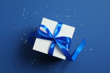 Beautiful gift box tied with bow on color background 