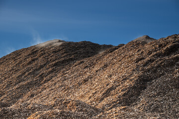 Huge pile of fresh woodchips against the sky.. pile woodchips.