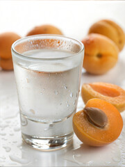 Chilled glass of water with fresh apricots on white background