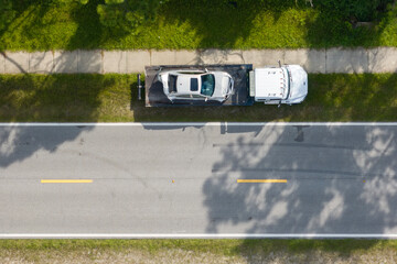 Tow truck loading crashed car on accident site. Emergency services personnel and vehicles responding to vehicle crash on American street. First responders helping on road in the USA