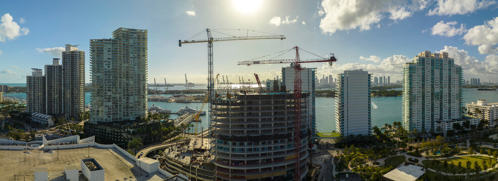 Tower lifting cranes at high residential apartment building construction site. Real estate development in Miami urban area