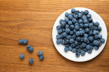 Fresh blueberries on white plate with wooden background
