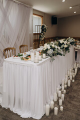Wedding presidium in white: draped table, golden chairs, hydrangea and rose arrangements, candle path.