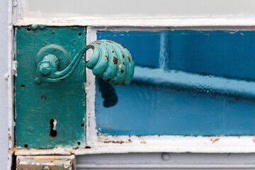 Vintage green forged handle of a metal door