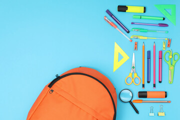 Backpack and different school supplies on light blue background, flat lay. Space for text